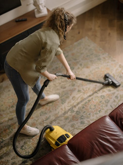 Three professional cleaners from Carpet Cleaning Streatham, a company near SW16, are performing surface cleaning and deep cleaning in a modern living room. The room features a light-colored tiled floo